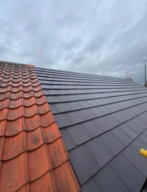 Rooftop with red terracotta tiles on left transitioning to dark gray slate tiles on right under cloudy sky